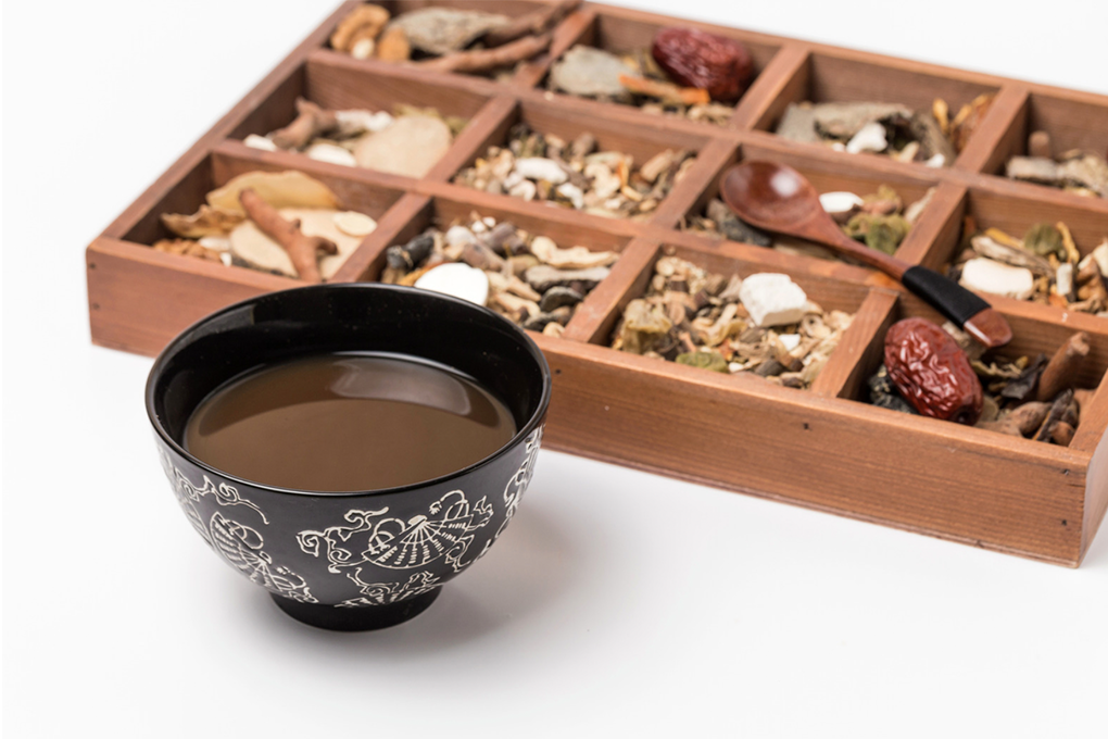 Wooden box with various herbs next to a cup of tea.